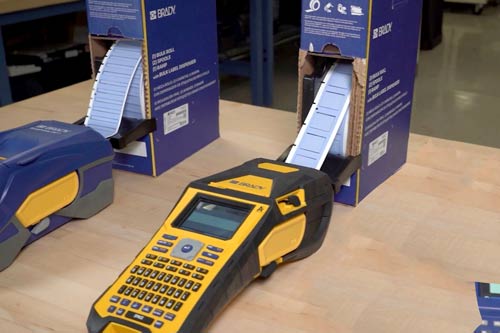 M610 etiket yazıcısına sürekli besleme yapan büyük bir etiket kutusu.