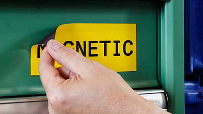 Bir kişi, metal raf üzerine manyetik bir etiket ayarlıyor.