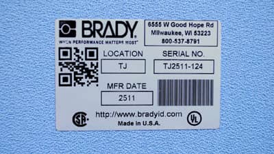 Girintili çıkıntılı bir yüzeye uygulanmış metalize ve parlak derecelendirme levhası etiketi.