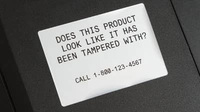 Bir ekipman parçasının girintili çıkıntılı kutusuna uygulanmış Brady çok amaçlı ultra-kuvvetli yapışkanlı etiket.