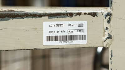 Depo rafının yıpranmış kenarına uygulanmış Brady ultra-kuvvetli yapışkanlı etiket.