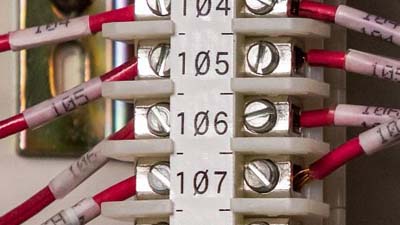 Beyaz bir terminal bloğu etiketi ve ayrı ayrı sarılabilir etiketlerle tanımlanmış sekiz kırmızı tel.