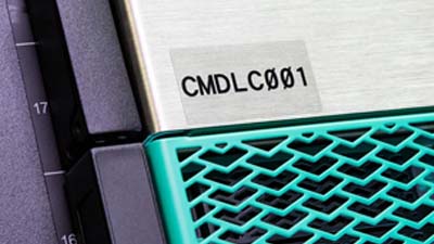 Siyah yazılı şeffaf polyester etiketli bir makine parçası.