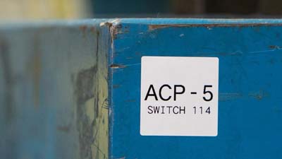 Bir ekipman üzerindeki beyaz bir etiket, üzerinde yazan: 