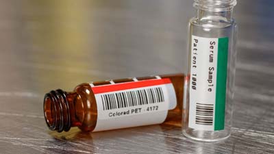 Kırmızı ve yeşil renkli polyester etiketlere sahip iki flakon.