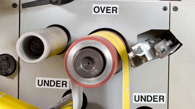 Malzemenin takılması gereken yönü belirtmek için kalıp kesme makinesine uygulanan, üzerinde OVER ve UNDER yazan tüm hava koşullarına uygun birkaç Brady vinil etiket.